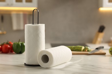 Photo of Rolls of paper towels and vegetables on white marble table in kitchen, space for text