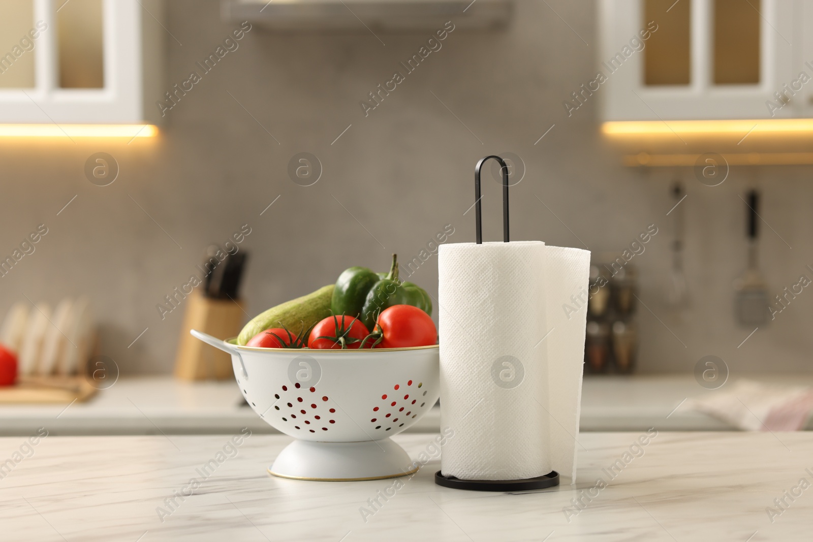 Photo of Roll of paper towels and vegetables on white marble table in kitchen