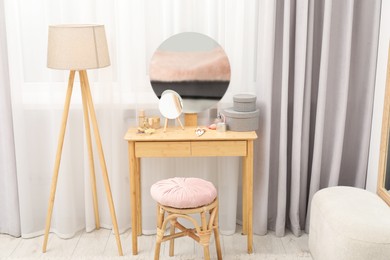 Photo of Mirror, dressing table, lamp and stool near window indoors. Interior design