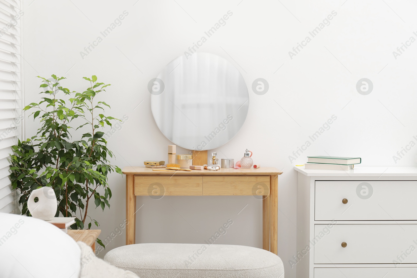 Photo of Mirror, dressing table, houseplant and chest of drawers indoors. Interior design