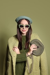 Photo of Young woman with stylish accessories on olive background