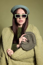 Photo of Young woman with stylish accessories on olive background