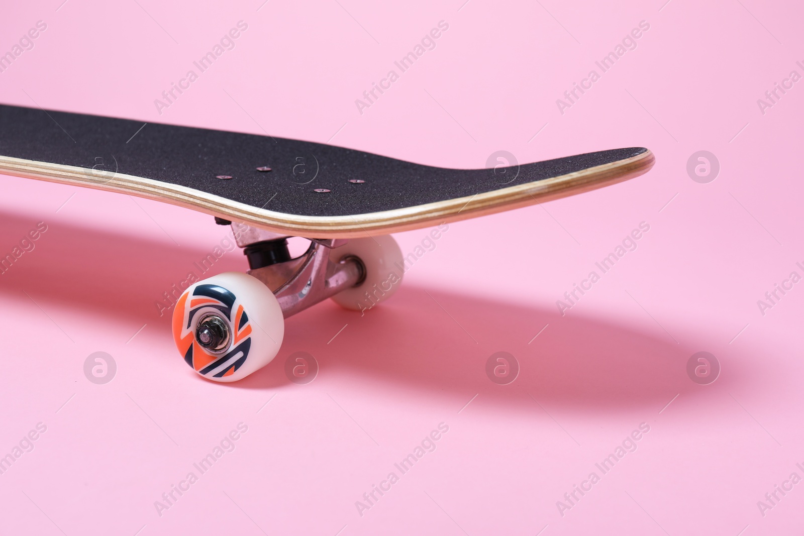 Photo of One skateboard on pink background, closeup. Sports equipment