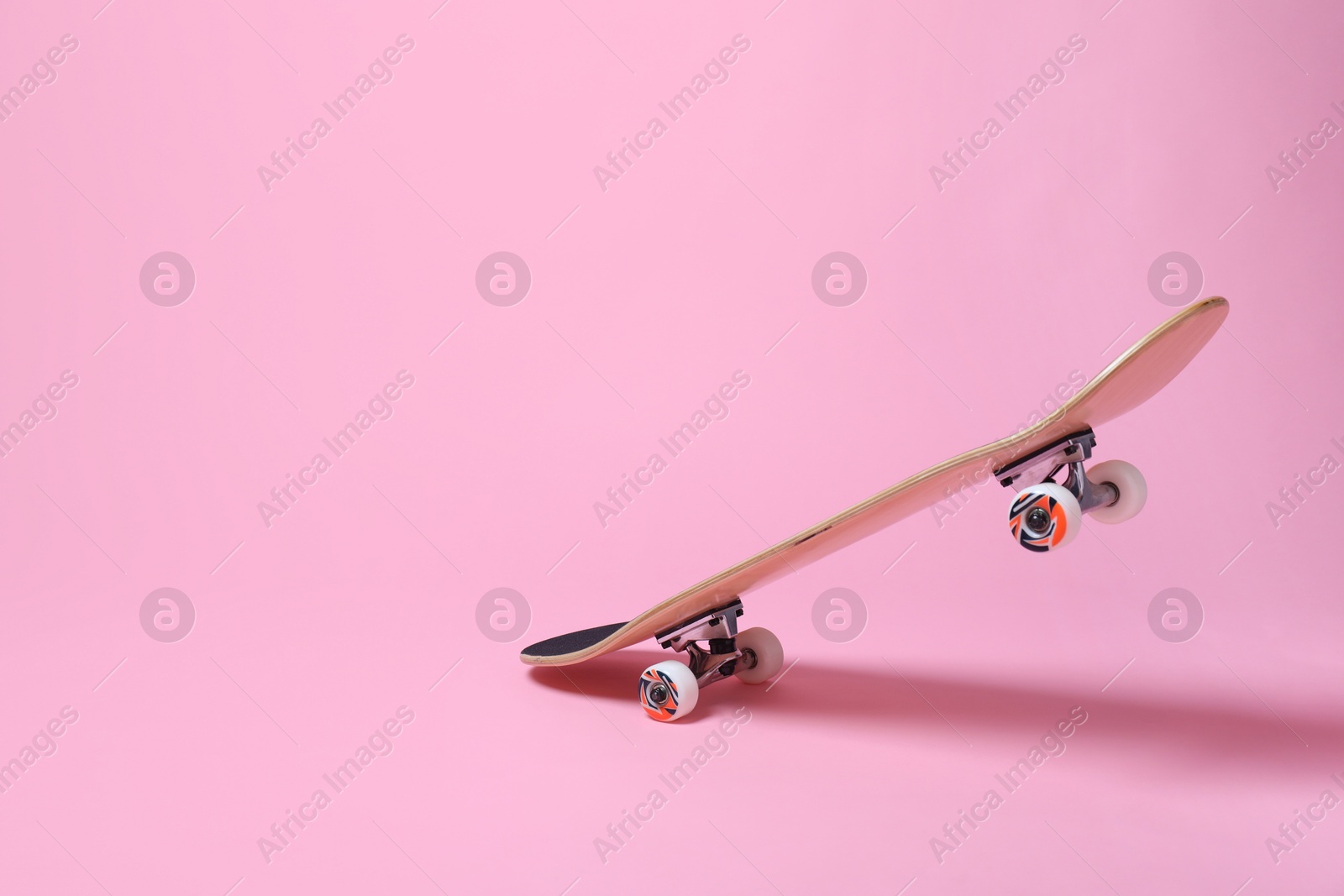 Photo of One skateboard on pink background, space for text. Sports equipment