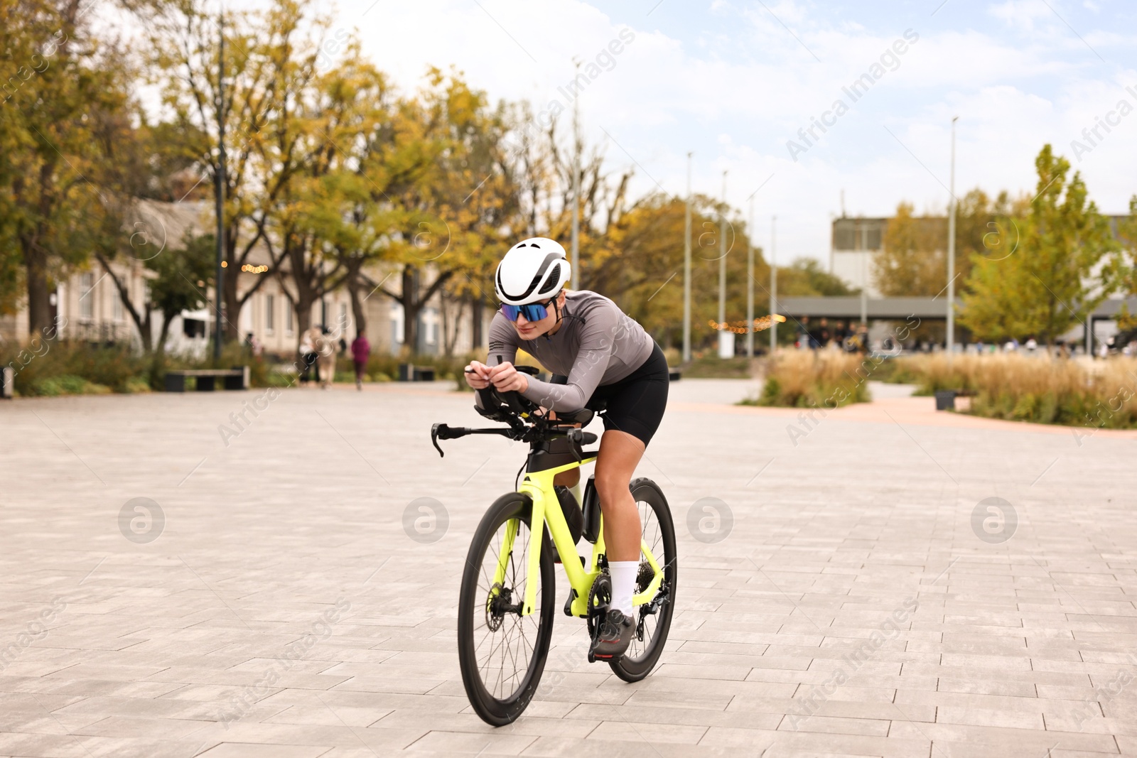 Photo of Young athletic woman with helmet riding bicycle outdoors