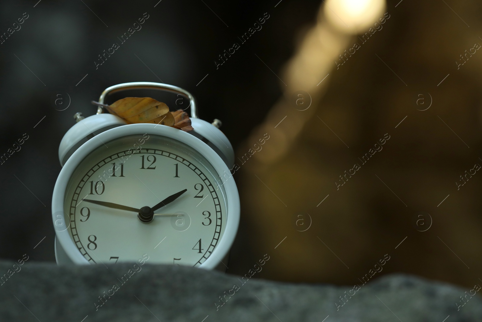 Photo of Alarm clock on stones outdoors, closeup. Space for text