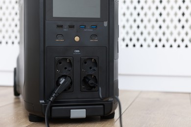 Photo of Modern portable power station on floor indoors, closeup