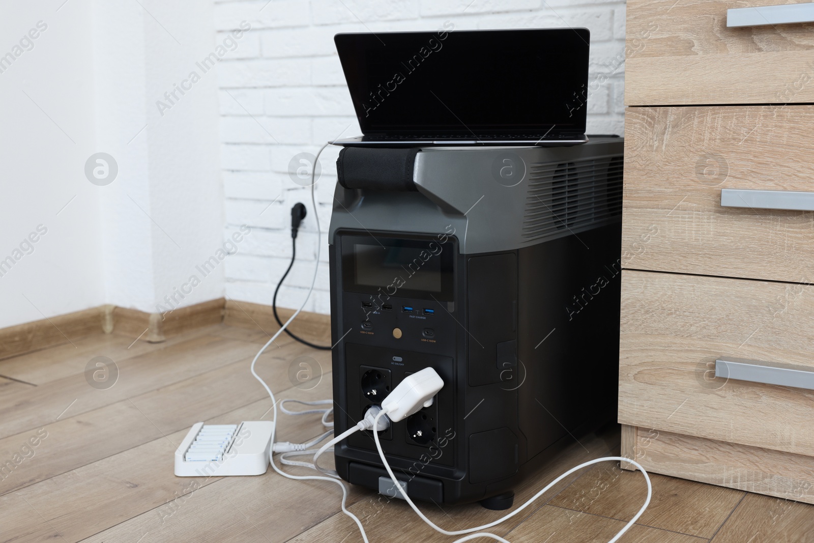 Photo of Modern portable power station, charging attached devices indoors