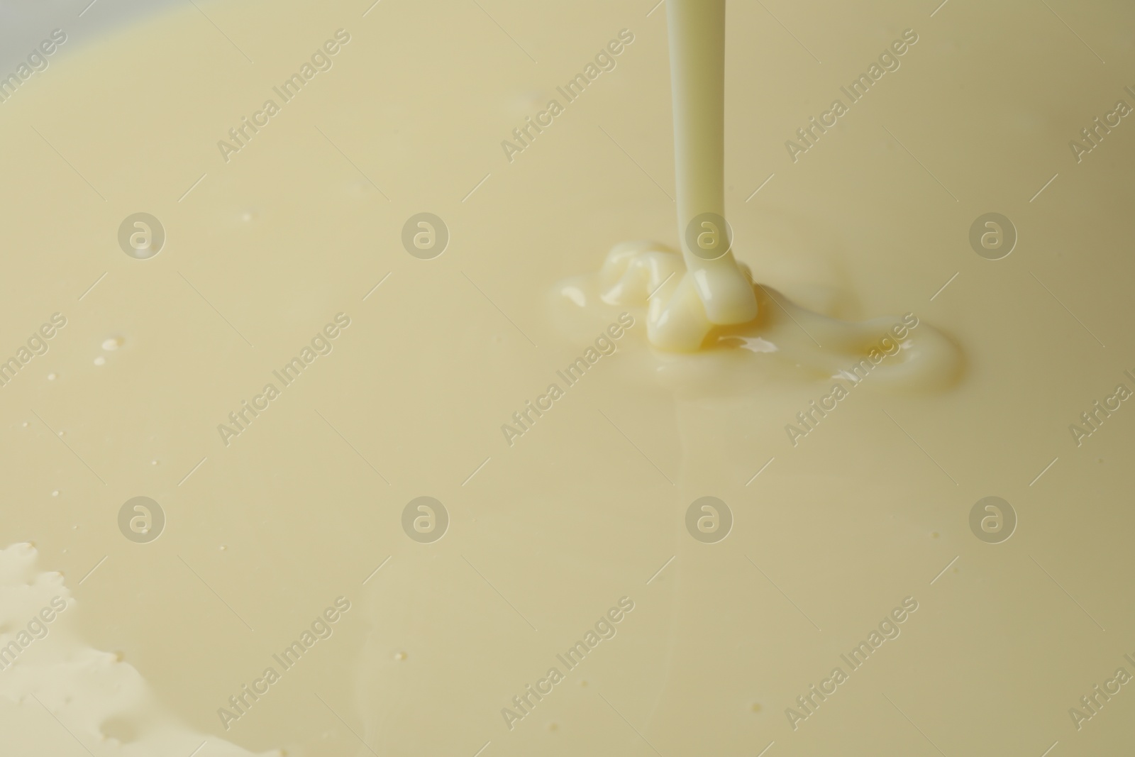 Photo of Pouring delicious condensed milk as background, closeup