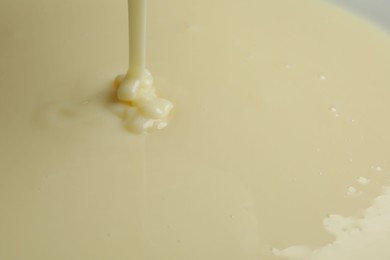 Photo of Pouring delicious condensed milk as background, closeup