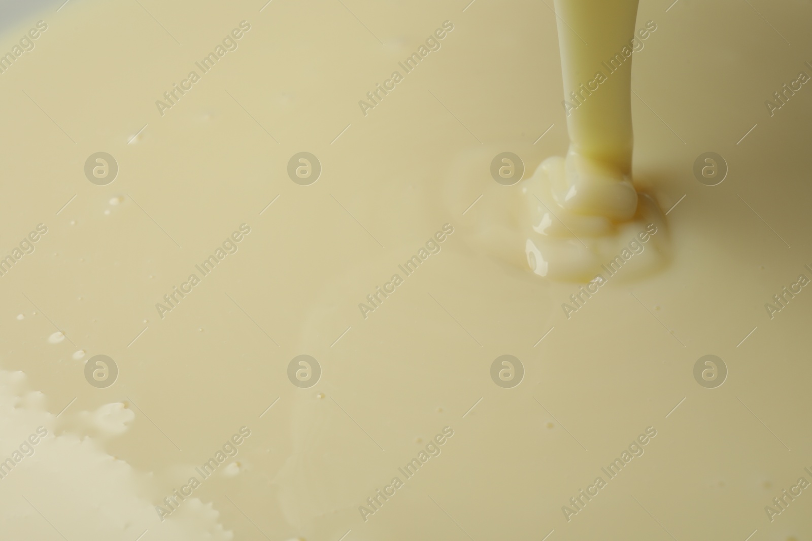 Photo of Pouring delicious condensed milk as background, closeup