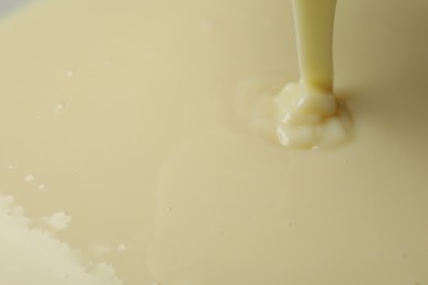 Photo of Pouring delicious condensed milk as background, closeup