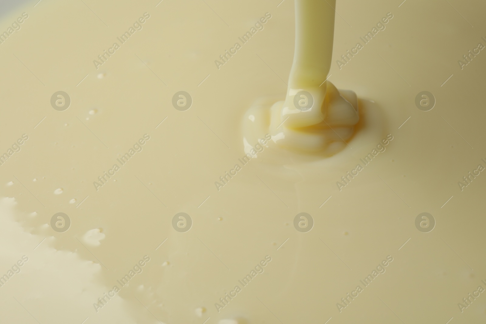 Photo of Pouring delicious condensed milk as background, closeup