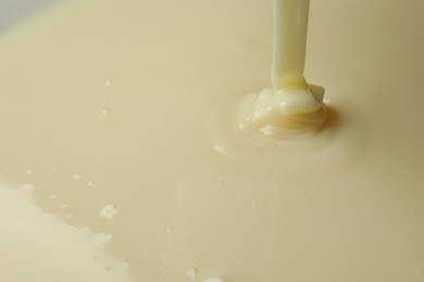 Photo of Pouring delicious condensed milk as background, closeup