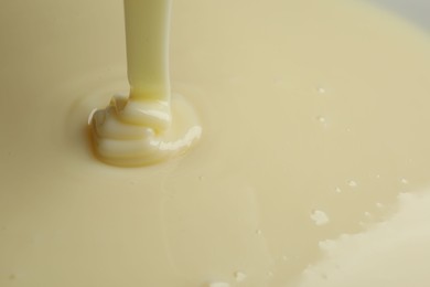 Photo of Pouring delicious condensed milk as background, closeup