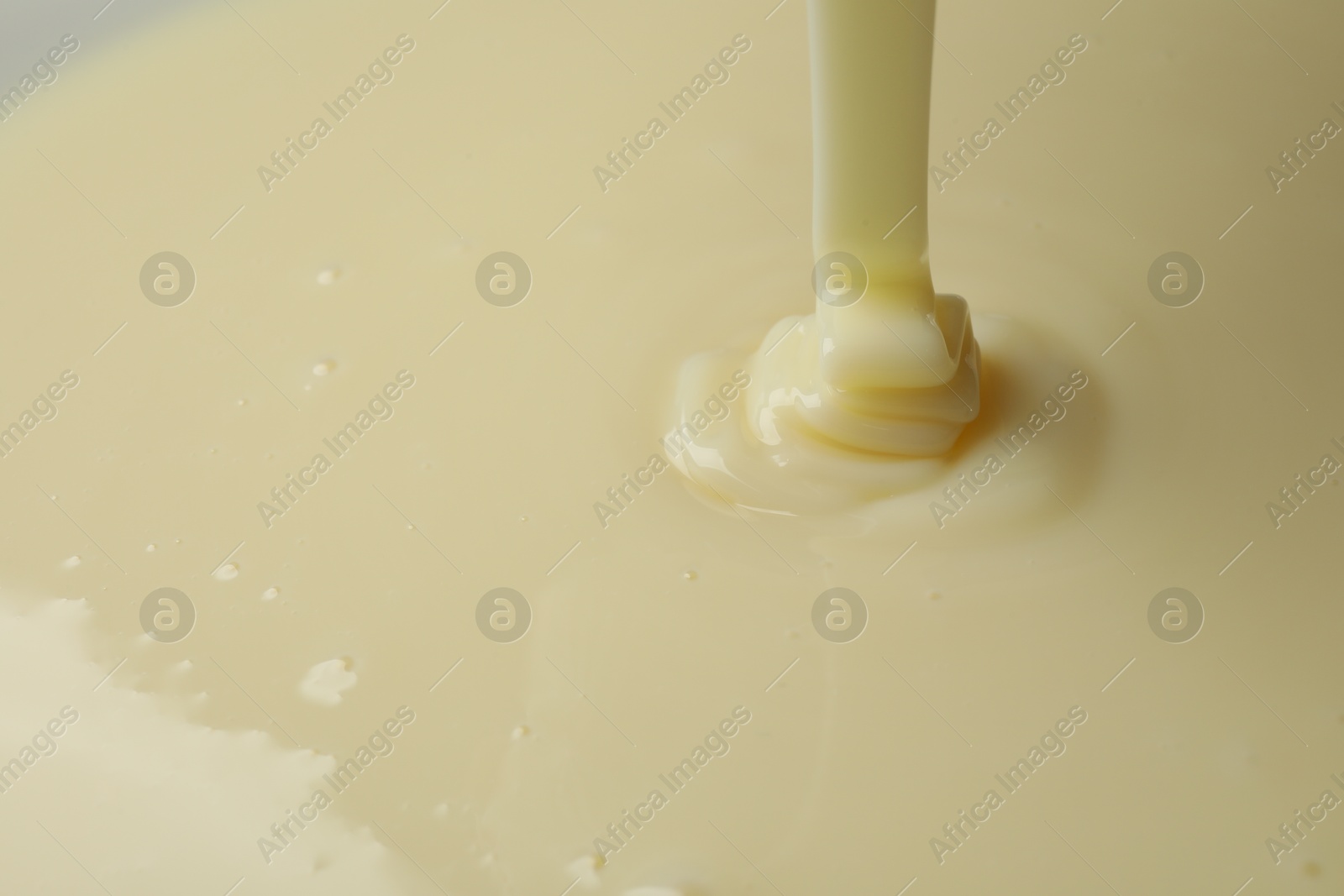 Photo of Pouring delicious condensed milk as background, closeup