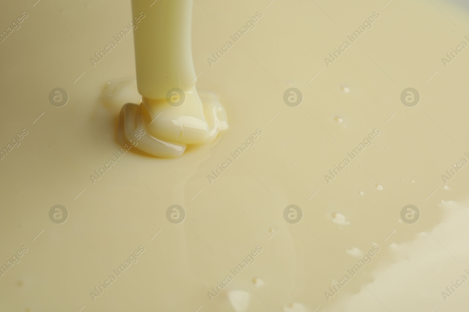 Photo of Pouring delicious condensed milk as background, closeup