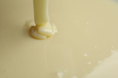 Photo of Pouring delicious condensed milk as background, closeup