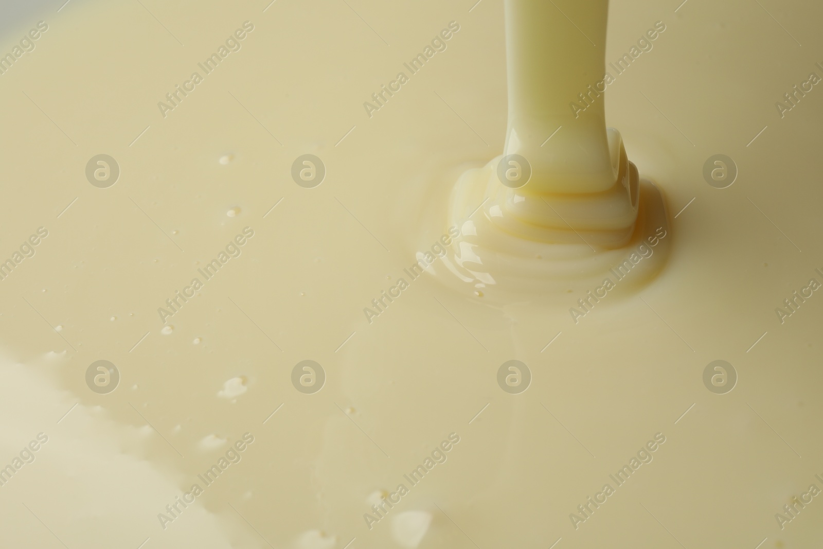 Photo of Pouring delicious condensed milk as background, closeup