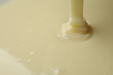 Photo of Pouring delicious condensed milk as background, closeup