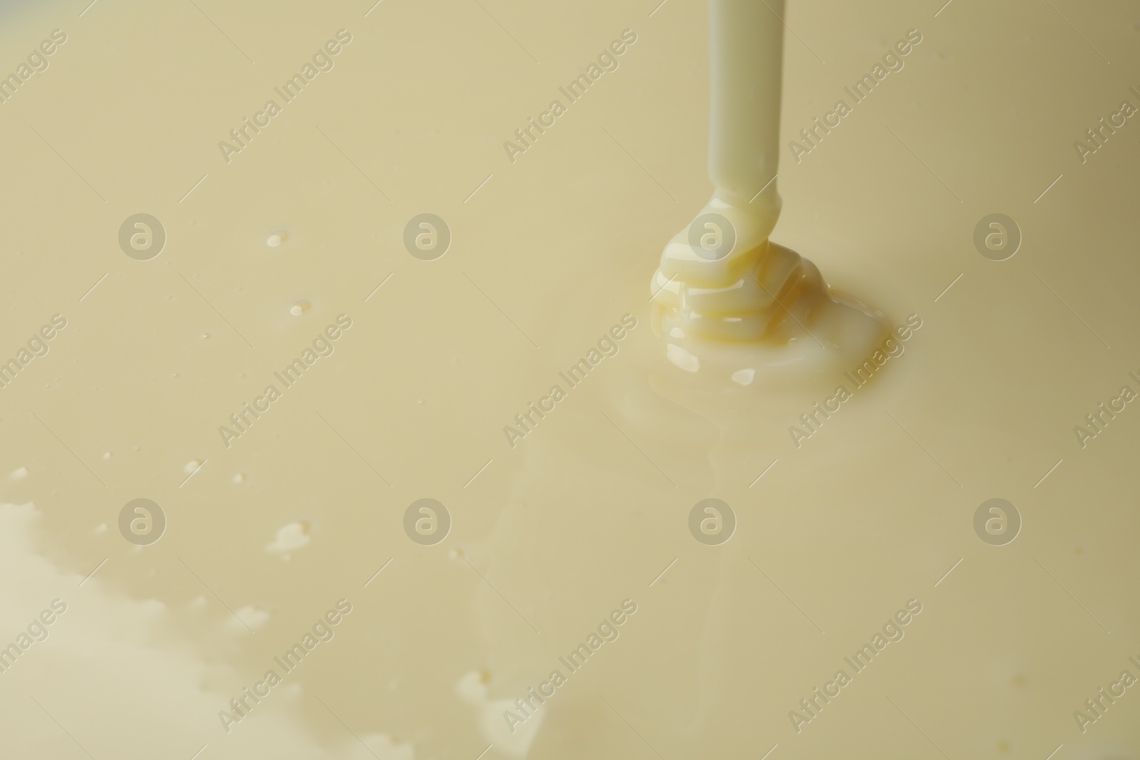 Photo of Pouring delicious condensed milk as background, closeup