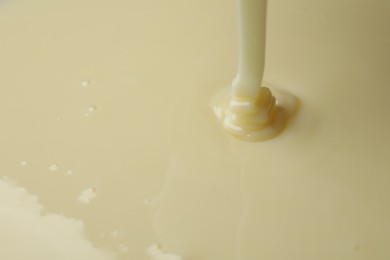 Photo of Pouring delicious condensed milk as background, closeup