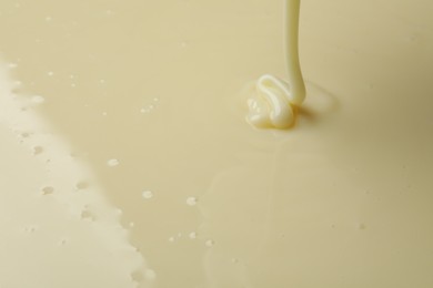 Photo of Pouring delicious condensed milk as background, closeup