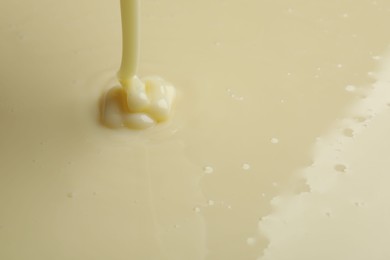 Photo of Pouring delicious condensed milk as background, closeup