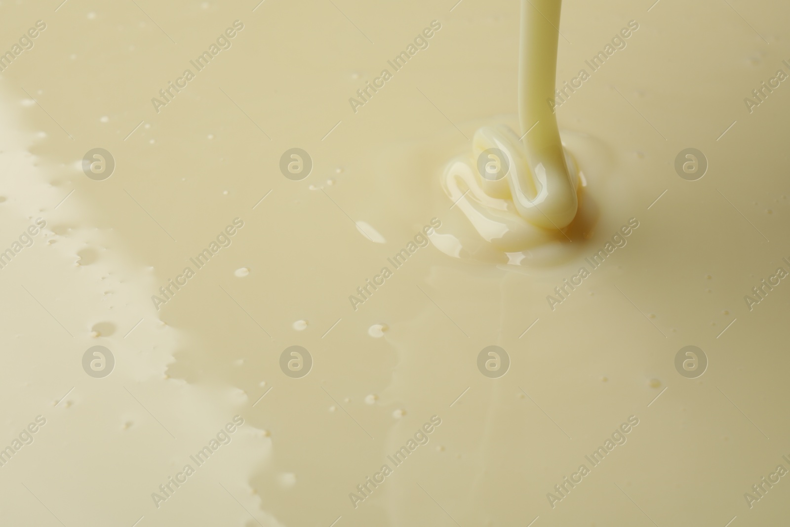 Photo of Pouring delicious condensed milk as background, closeup