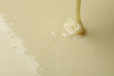 Photo of Pouring delicious condensed milk as background, closeup