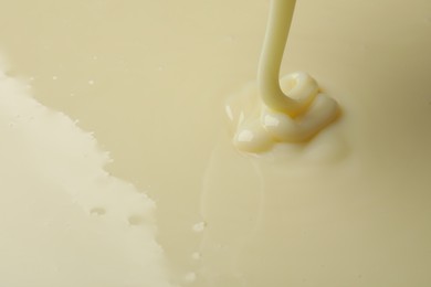 Photo of Pouring delicious condensed milk as background, closeup