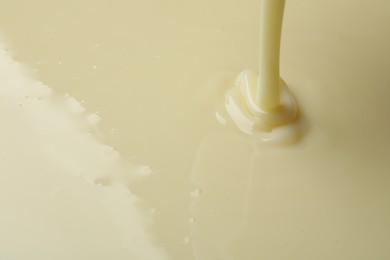 Photo of Pouring delicious condensed milk as background, closeup