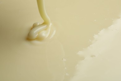 Photo of Pouring delicious condensed milk as background, closeup