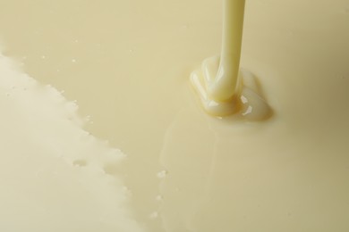 Photo of Pouring delicious condensed milk as background, closeup