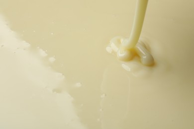 Photo of Pouring delicious condensed milk as background, closeup