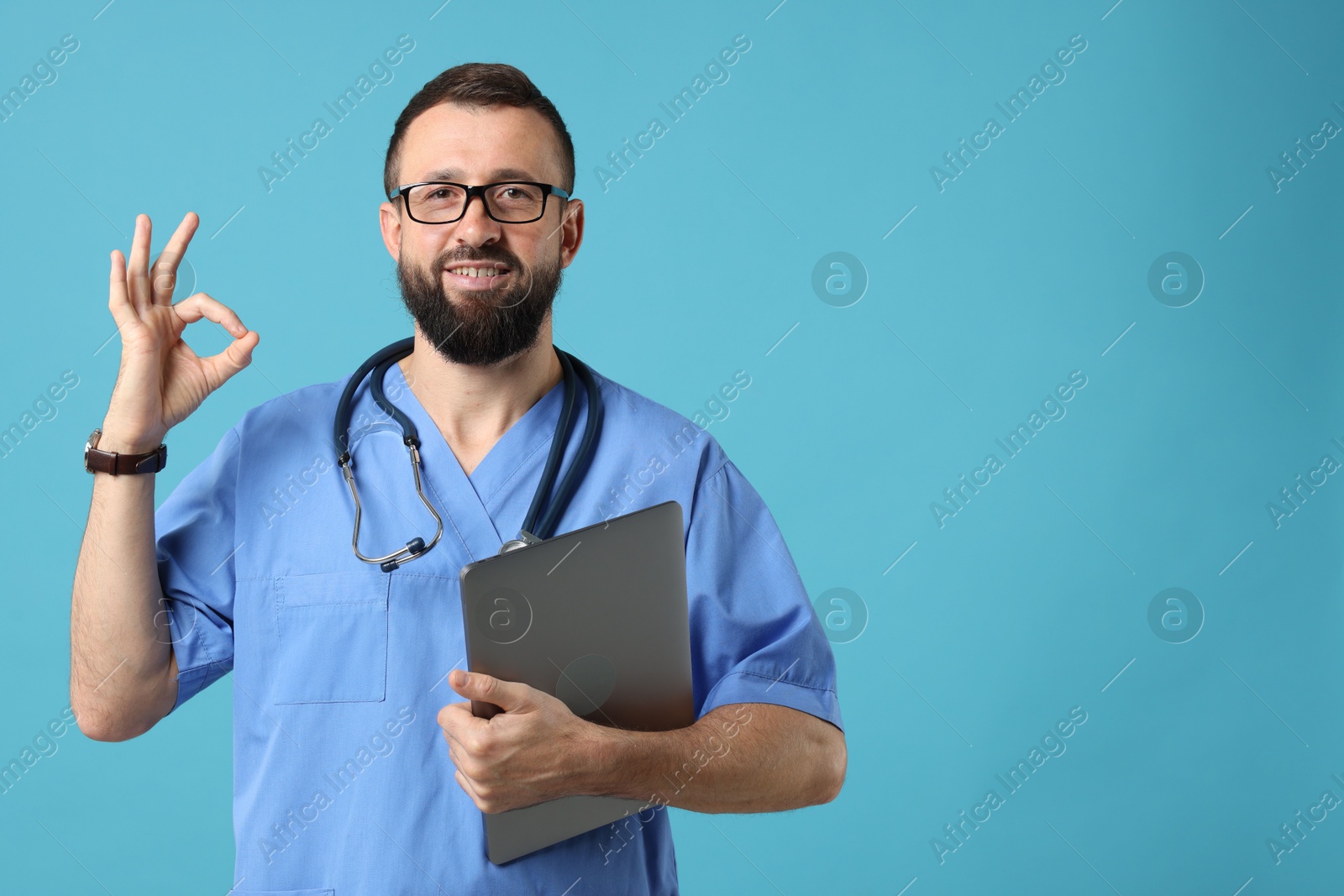 Photo of Doctor with laptop showing okay gesture on light blue background. Space for text