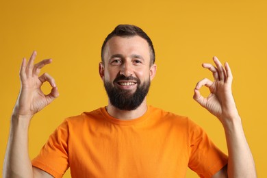 Photo of Happy man showing okay gesture on orange background