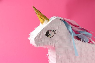 Photo of Bright pinata in shape of unicorn on pink background