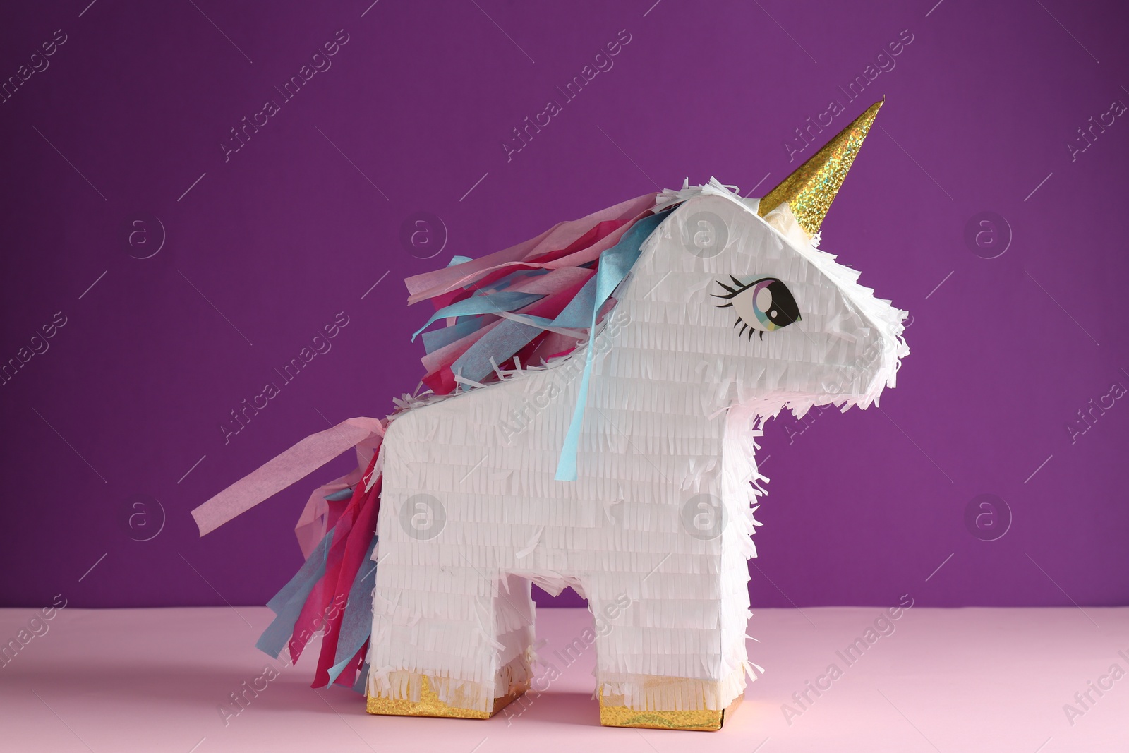 Photo of Bright pinata in shape of unicorn on color background