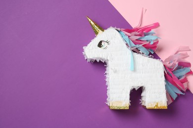 Photo of Bright pinata in shape of unicorn on color background, top view. Space for text