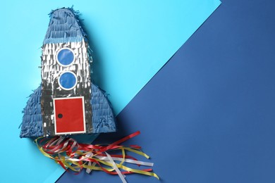 Photo of Bright pinata in shape of spaceship on blue background, top view. Space for text