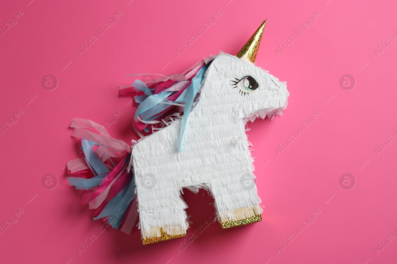 Photo of Bright pinata in shape of unicorn on pink background, top view