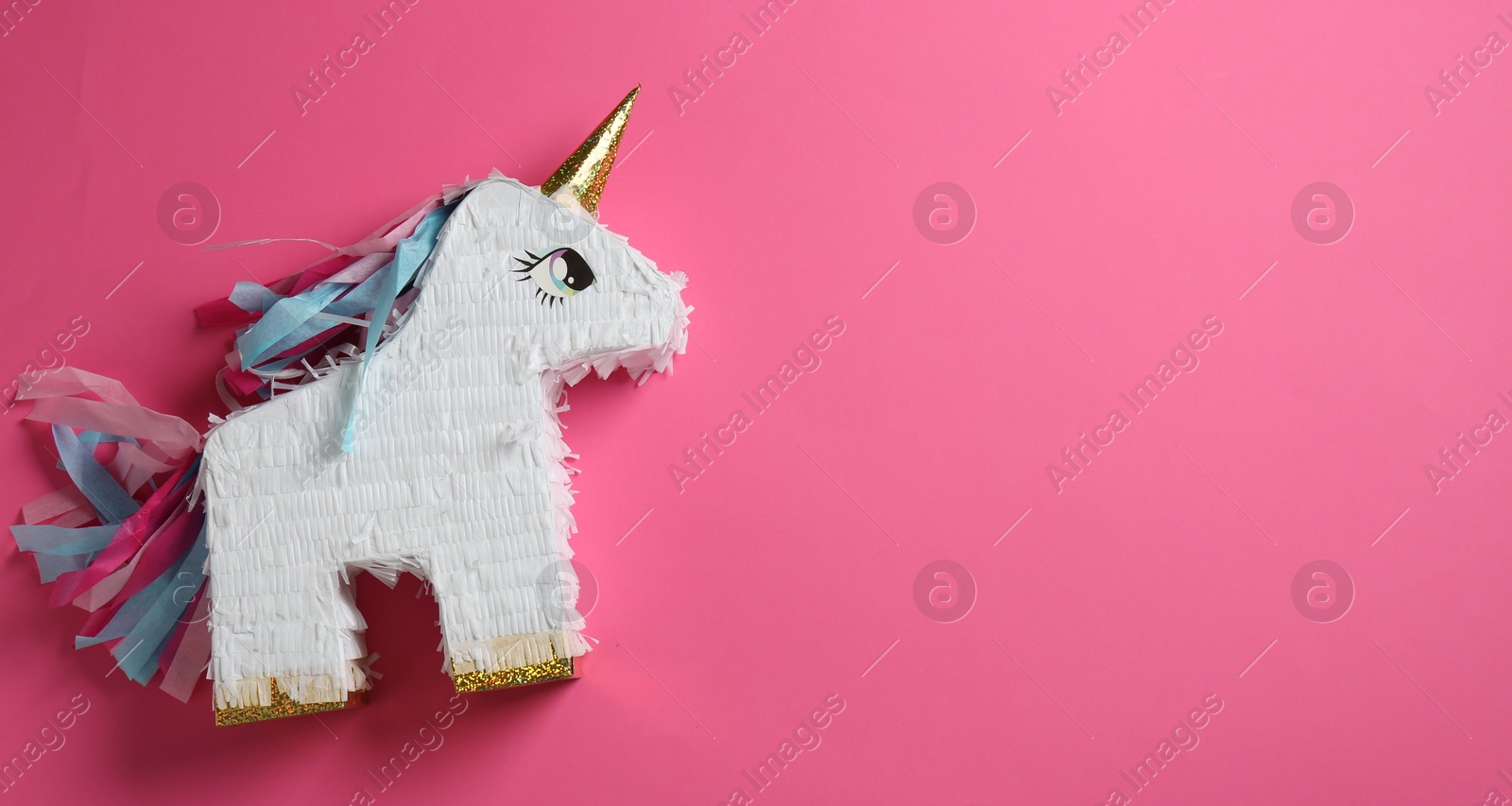 Photo of Bright pinata in shape of unicorn on pink background, top view. Space for text