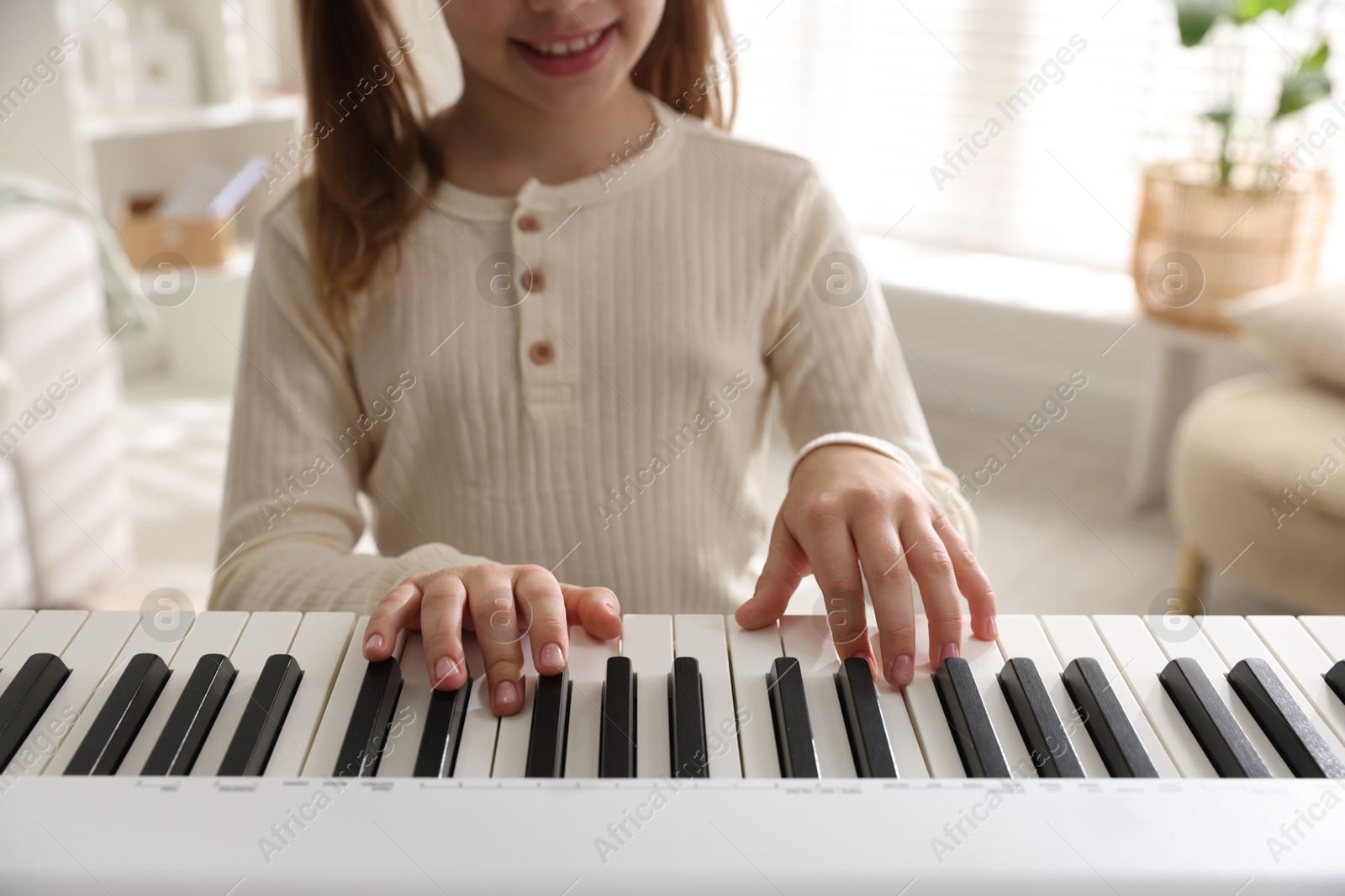 Photo of Girl playing synthesizer indoors, closeup. Electronic musical instrument