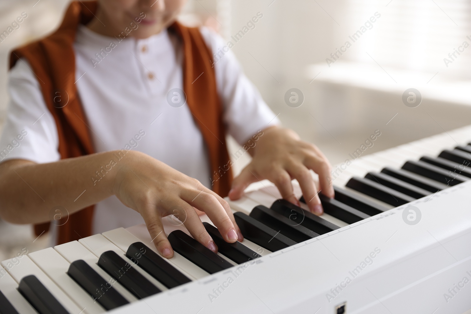 Photo of Boy playing synthesizer indoors, closeup. Electronic musical instrument