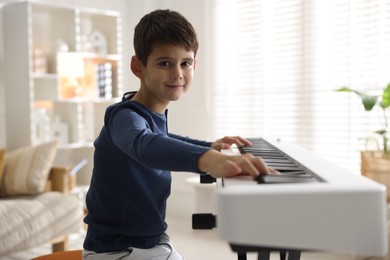 Photo of Cute boy playing synthesizer at home. Electronic musical instrument