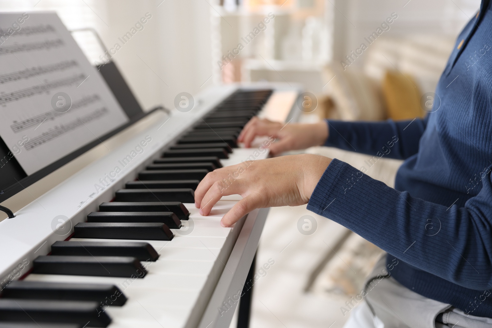 Photo of Boy playing synthesizer indoors, closeup. Electronic musical instrument