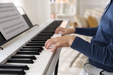 Photo of Boy playing synthesizer indoors, closeup. Electronic musical instrument