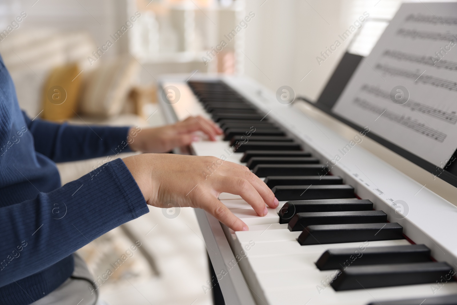 Photo of Boy playing synthesizer indoors, closeup. Electronic musical instrument