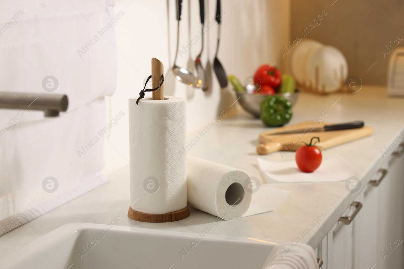 Photo of Rolls of paper towels on white marble countertop near sink in kitchen